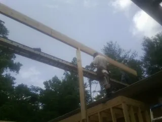 Carpenter setting a ridge beam over a new addition frame — Ice Dam Removal by Roofing Brothers in Vestal