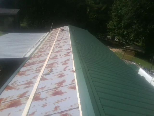 Old rusted panels beside newly installed green metal roofing — Wind Damage Roof Repair by Roofing Brothers in Vestal