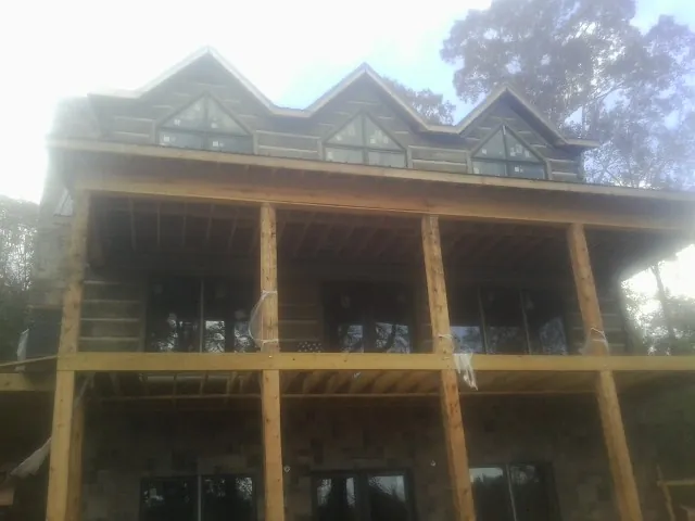 Dormers and porch framing on a large log home under construction — Roof Coating work by our crew in Vestal