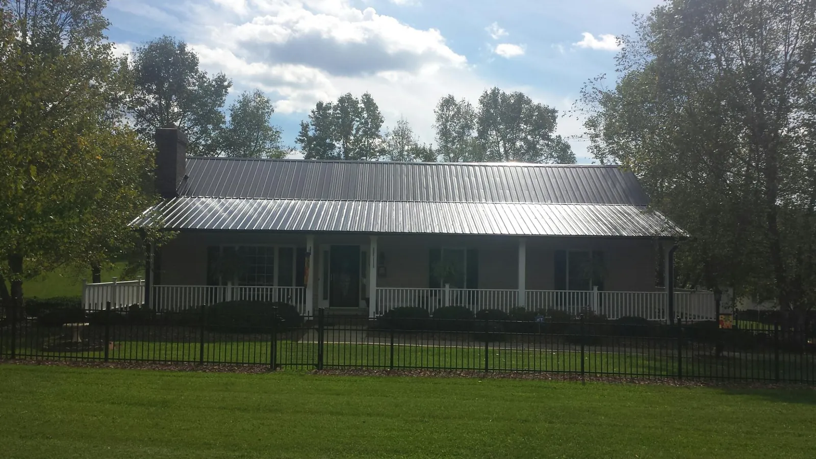 Gray metal roof on a brick ranch with a full width front porch — Gutter Guard Installation work by our crew in Vestal