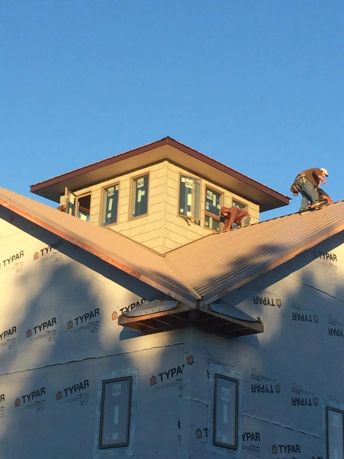 Roofers working around a rooftop cupola on a new metal roof at sunset — Roof Waterproofing in Vestal by Roofing Brothers